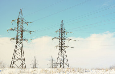 Towers of power lines in the winter field. Electrical equipment