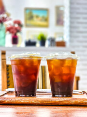 Two plastic coffee cups with lids holding coffee are on the table.
