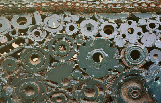A composition of a set of gears and car parts that are welded to each other and painted green. Grunge steampunk texture