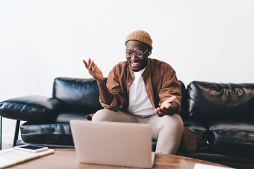 Cheerful African American guy talking on laptop