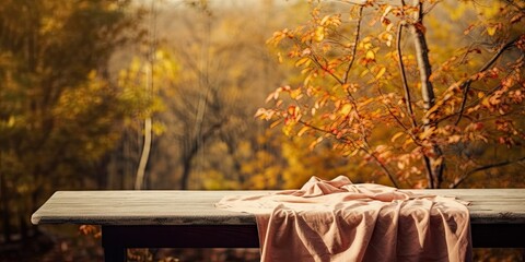 Rustic autumn comfort. Warm textile and knitted sweater on empty vintage wooden table. Cozy knits. Background and leaves. Seasonal charm
