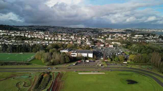 Paignton, Torbay, South Devon, England: DRONE VIEWS: Cyclo-cross cycling event at Torbay VeloPark. SHOWS: Track; Cyclists; Paignton skyline and Torbay Leisure Centre / car park in background (Clip 3).