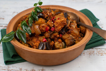 Vegan Indian curry with mock meat eggplant,  seitan, plant based  protein. Served in clay dish.