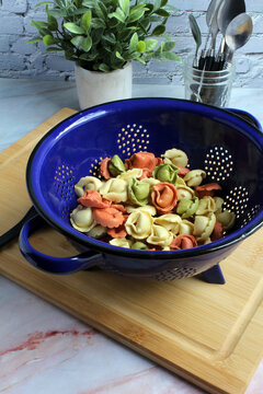 Fresh tri-color tortellini in a colander, ready to cook.