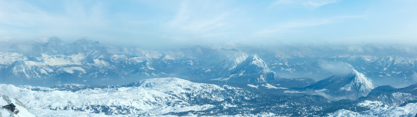 Fototapeta na wymiar Winter hazy view from Dachstein mountain massif top and house on rocky slope (Austria).