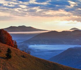 Morning fog in autumn Carpathian. Mountain top daybreak landscape.