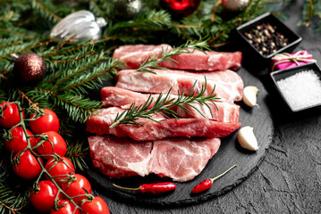 Christmas raw pork steaks on a background of a Christmas tree and Christmas toys