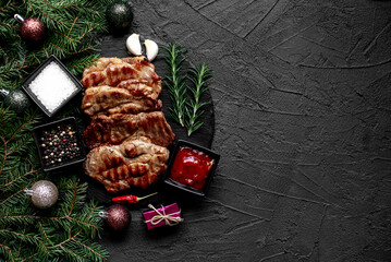 Christmas grilled pork steaks on a background of a Christmas tree and Christmas decorations with copy space for your text