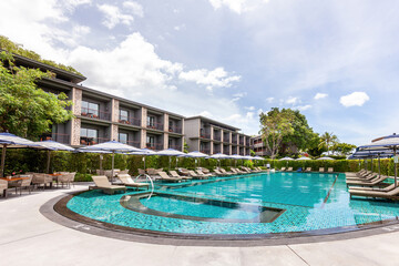 Luxurious hotel complex with large swimming pool, sun loungers, and parasols for guest leisure activities