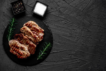 grilled pork steaks on stone background with copy space for your text	