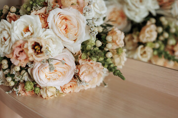 Close-up of peach and white roses in a bouquet on a wooden surface. Concept of expressing love, gratitude, sympathy or congratulations with a beautiful floral gift.