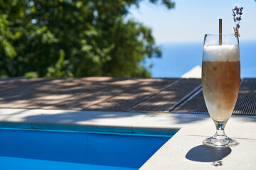 Cold coffee by the swimmingpool on the background of the sea. Front view. Copy space. Summertime. Travels. Vacation.