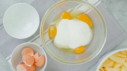 Mix of eggs and sugar close-up in a glass bowl, flat lay. Apple cake recipe