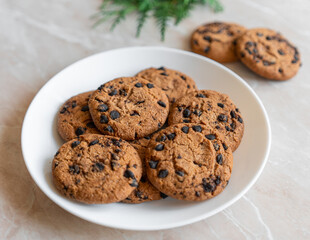 Chocolate cookies on a plate with spruce branches on the table. Dark chocolate cookies on a plate, Christmas cookies chocolate cinnamon sweet dessert holiday treat new year and christmas food