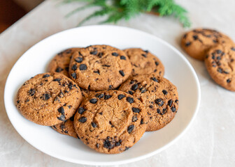 Chocolate cookies on a plate with spruce branches on the table. Dark chocolate cookies on a plate, Christmas cookies chocolate cinnamon sweet dessert holiday treat new year and christmas food