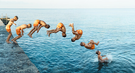 Sequence of front flip jump. Moments of schoolboy jumping from stone pier into sea at sunrise doing...