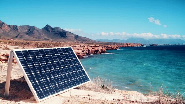 Solar photovoltaic panels, charging batteries outdoors on sea shore. Renewable eco energy concept