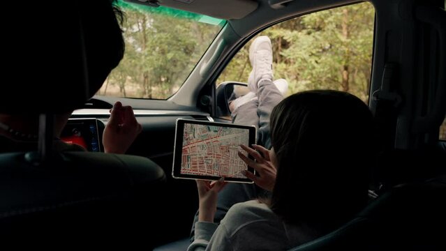 A couple in a car conferring and planning the best route through the forest using map on tablet