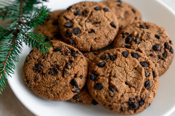 Chocolate cookies on a plate with spruce branches on the table. Dark chocolate cookies on a plate, Christmas cookies chocolate cinnamon sweet dessert holiday treat new year and christmas food