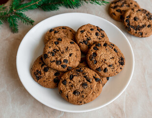 Chocolate cookies on a plate with spruce branches on the table. Dark chocolate cookies on a plate, Christmas cookies chocolate cinnamon sweet dessert holiday treat new year and christmas food