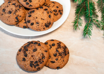 Chocolate cookies on a plate with spruce branches on the table. Dark chocolate cookies on a plate, Christmas cookies chocolate cinnamon sweet dessert holiday treat new year and christmas food