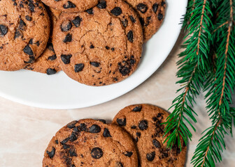 Chocolate cookies on a plate with spruce branches on the table. Dark chocolate cookies on a plate, Christmas cookies chocolate cinnamon sweet dessert holiday treat new year and christmas food