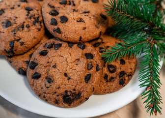 Chocolate cookies on a plate with spruce branches on the table. Dark chocolate cookies on a plate, Christmas cookies chocolate cinnamon sweet dessert holiday treat new year and christmas food