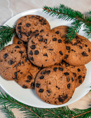Chocolate cookies on a plate with spruce branches on the table. Dark chocolate cookies on a plate, Christmas cookies chocolate cinnamon sweet dessert holiday treat new year and christmas food