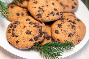 Chocolate cookies on a plate with spruce branches on the table. Dark chocolate cookies on a plate, Christmas cookies chocolate cinnamon sweet dessert holiday treat new year and christmas food