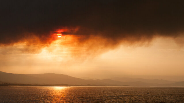 Sol tapado por columna de humo en incendio junto al mar