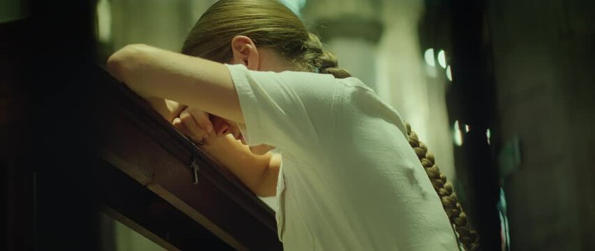 Woman praying on her knees in church. Sincerely believing girl prays to God for forgiveness of sins.