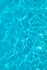 Azure transparent texture of water in a blue pool with splashes from the sun