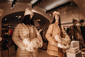 Two female mannequins dressed in a stylish brown beige warm coat. Autumn winter fashion collection