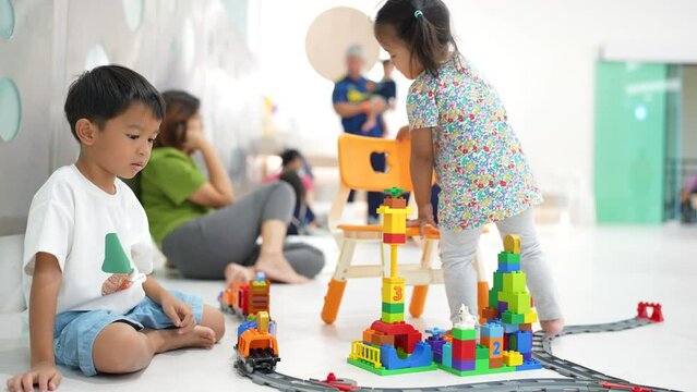 Happy kindergarten kid boy and girl enjoying play building toy block in class imagination learnning concept