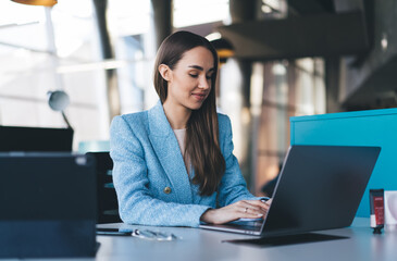 Positive woman working on laptop in office