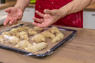 Croissant in man hands. Cooking process.