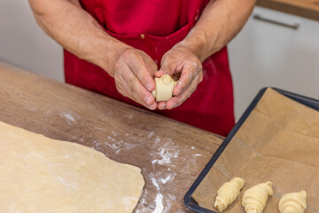 Croissant in man hands. Cooking process.