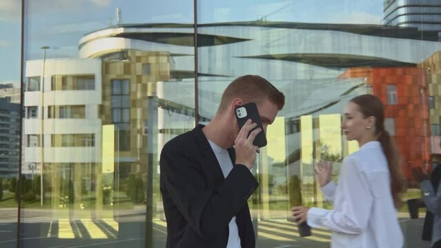 Side view of stylish office worker walking outdoors and consulting client talking mobile phone, young adviser inform customer about changing and business deal. Professional occupation concept