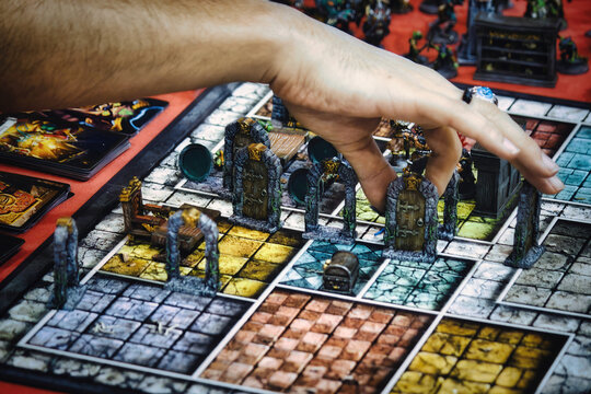 Close-up of someone's hand picking up a playing piece on the board of role-playing game Hero Quest