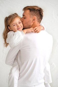A loving Dad with his daughter in his arms kisses her gently on the cheek. World Father's Day