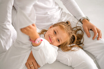 A sweet, beautiful, smiling Daughter is lying on her father's lap. Portrait of a child in close-up