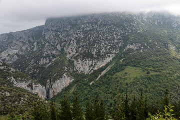 Fototapeta na wymiar Huge mountains with pine trees and lush vegetation covered by gray clouds.