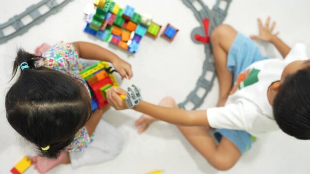 Adorable little kindergarten boy and girl playing plastic building block learnning education with toy