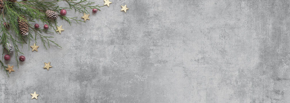 Coniferous tree twigs with cones, red fruits and scattered stars against the background of a concrete slab