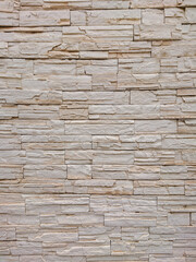 Beige stone wall vertical texture with stacked bricks, ideal for architectural backgrounds, home decor, and construction design