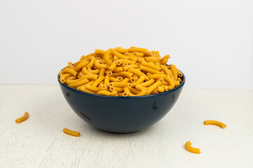 pasta horns in a deep blue bowl on a white background
