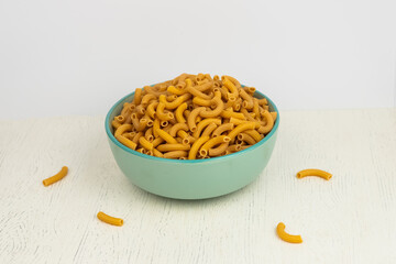 pasta horns in a green bowl on a white background