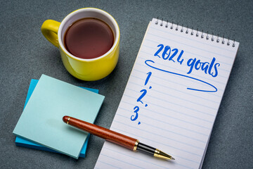 2024 goals list in a notebook with pen and coffee, setting New Year goals and resolutions - obrazy, fototapety, plakaty