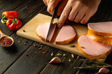 The cook cuts scalded sausage into small pieces for making sandwiches. Street food or fast food...