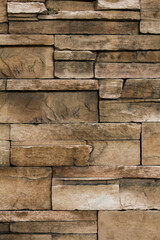 Obraz premium Vertical brown stone wall texture showcasing stacked bricks for rustic architectural backgrounds, construction designs, and home decor themes.